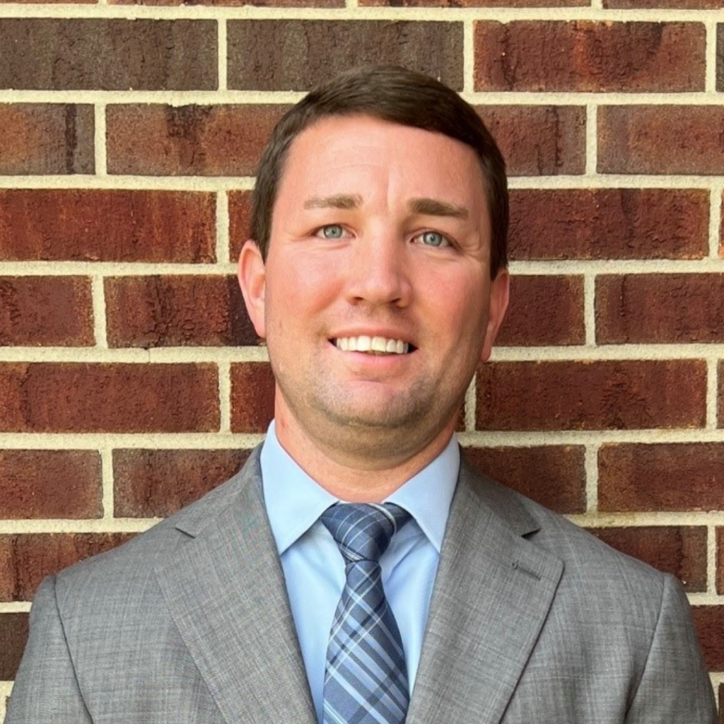 John Pilkington - Howes Law Firm - Attorney in Cedar Rapids Iowa Headshot of Attorney John Pilkington with Howes Law Firm in Cedar Rapids, standing in front of a brick wall in a suit and tie
